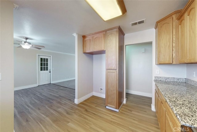 kitchen featuring ceiling fan, light brown cabinets, light stone counters, and light hardwood / wood-style flooring