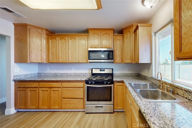 kitchen with light stone countertops, sink, light hardwood / wood-style flooring, and stainless steel appliances