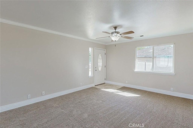 spare room featuring ceiling fan, light colored carpet, ornamental molding, and a healthy amount of sunlight