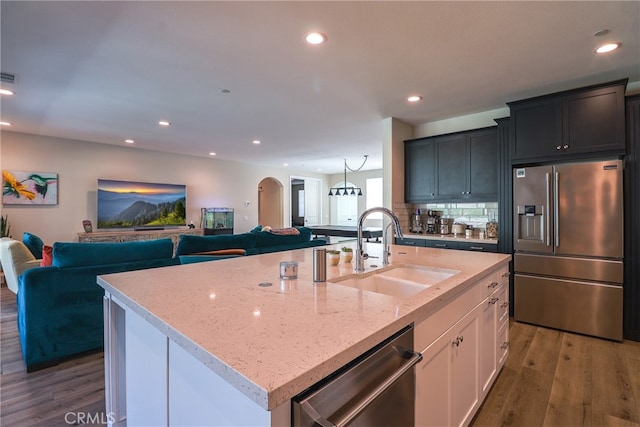 kitchen featuring sink, a center island with sink, backsplash, appliances with stainless steel finishes, and dark hardwood / wood-style floors