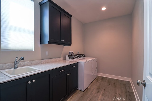 laundry area featuring separate washer and dryer, cabinets, light hardwood / wood-style flooring, and sink