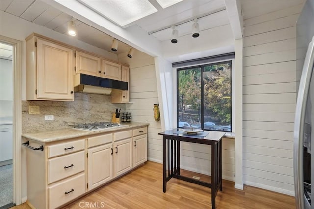 kitchen with light wood-type flooring, stainless steel appliances, wooden walls, and track lighting