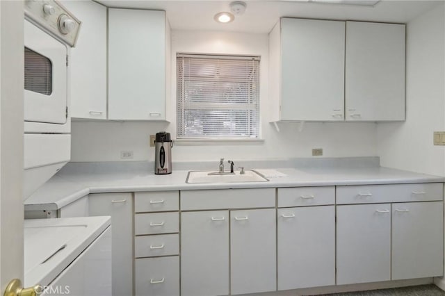 kitchen with white cabinets, stacked washer / drying machine, and sink