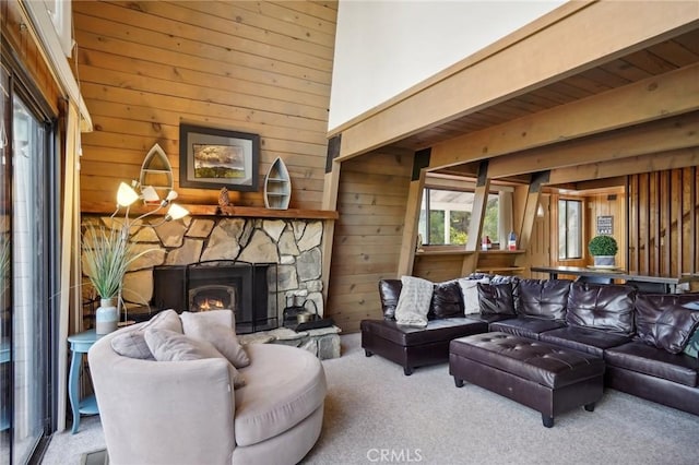 carpeted living room featuring a stone fireplace and wood walls