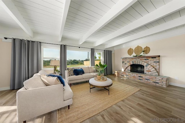 living room with wood ceiling, a brick fireplace, light hardwood / wood-style floors, and beamed ceiling