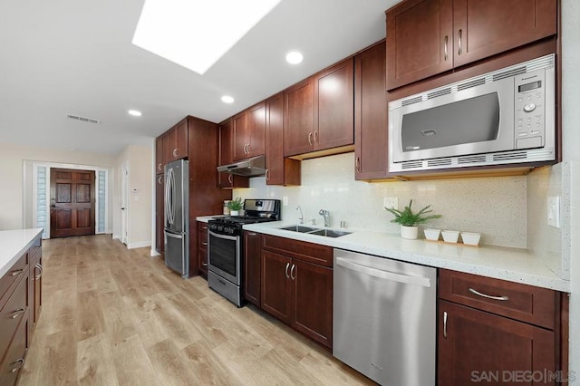 kitchen featuring light hardwood / wood-style floors, light stone counters, tasteful backsplash, stainless steel appliances, and sink