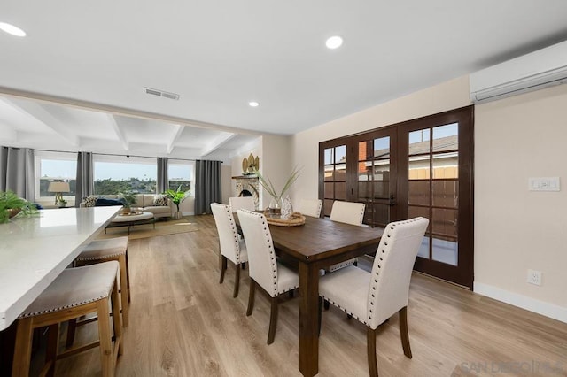 dining space featuring french doors, beamed ceiling, light hardwood / wood-style flooring, and a wall unit AC