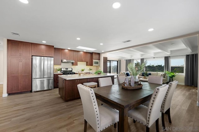 dining space featuring beam ceiling, a skylight, and hardwood / wood-style floors