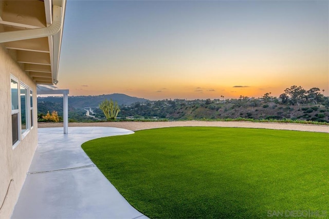 yard at dusk featuring a mountain view and a patio area