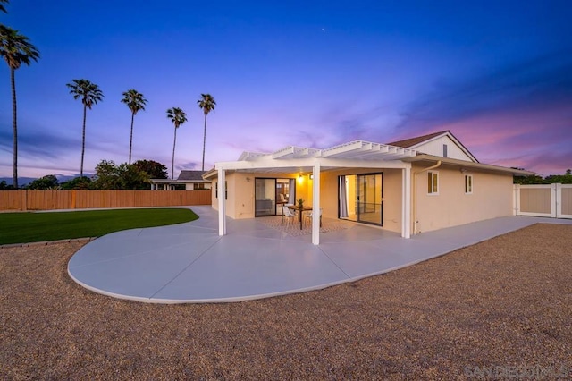 back house at dusk featuring a patio area