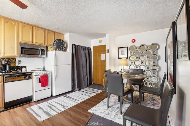 kitchen featuring ceiling fan, light brown cabinets, white appliances, light hardwood / wood-style flooring, and backsplash