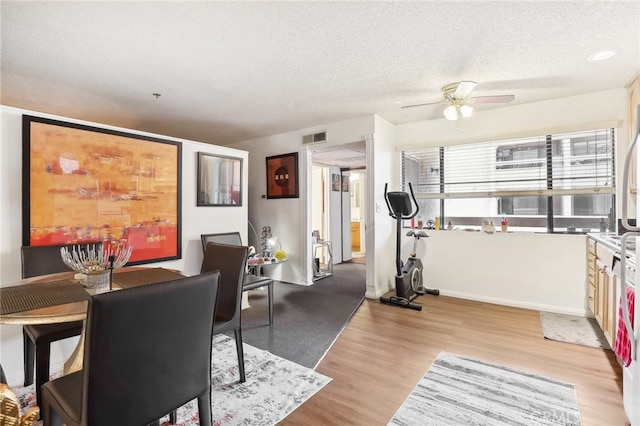 interior space with ceiling fan, a textured ceiling, and light hardwood / wood-style flooring