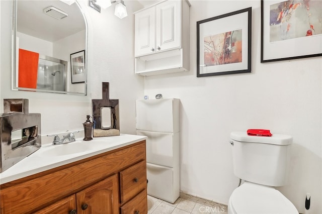 bathroom with tile patterned flooring, a shower with shower door, vanity, and toilet