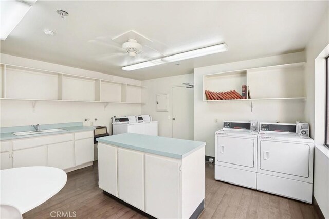 laundry room with light hardwood / wood-style floors, electric panel, sink, independent washer and dryer, and ceiling fan