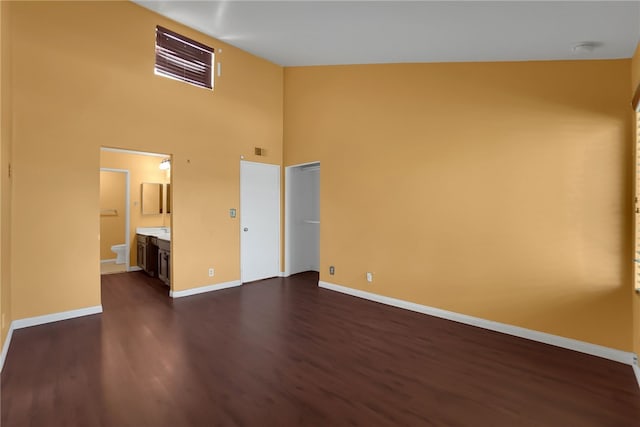 unfurnished bedroom featuring ensuite bathroom, high vaulted ceiling, and dark wood-type flooring