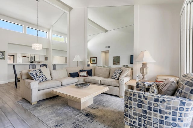 living room featuring wood-type flooring, a high ceiling, and an inviting chandelier