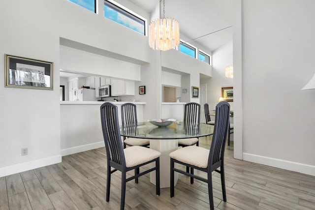 dining area featuring light hardwood / wood-style floors, a high ceiling, a chandelier, and a wealth of natural light