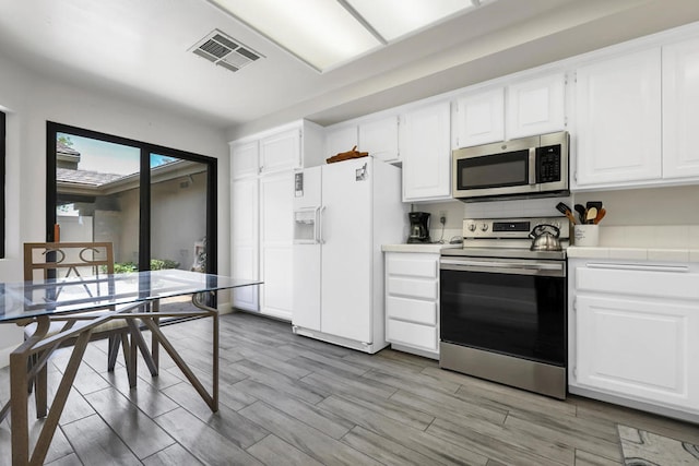 kitchen with light hardwood / wood-style flooring, stainless steel appliances, and white cabinets