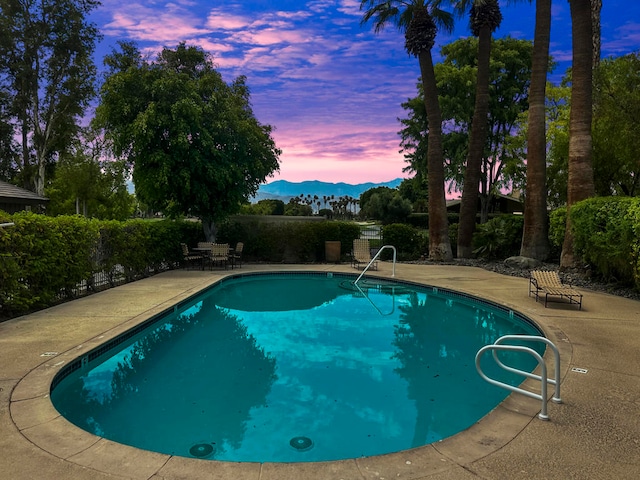 pool at dusk with a patio and a mountain view