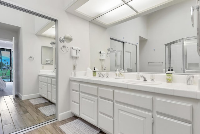 bathroom featuring wood-type flooring, a shower with door, and vanity