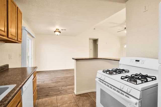 kitchen with a textured ceiling, white appliances, vaulted ceiling, ceiling fan, and light hardwood / wood-style floors