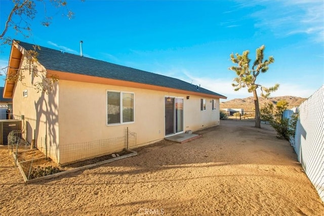 back of property with central AC unit and a mountain view