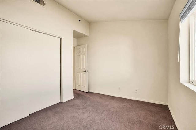 unfurnished bedroom with dark carpet and a closet