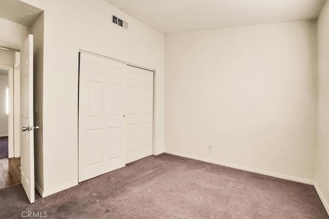 unfurnished bedroom with dark carpet and a closet