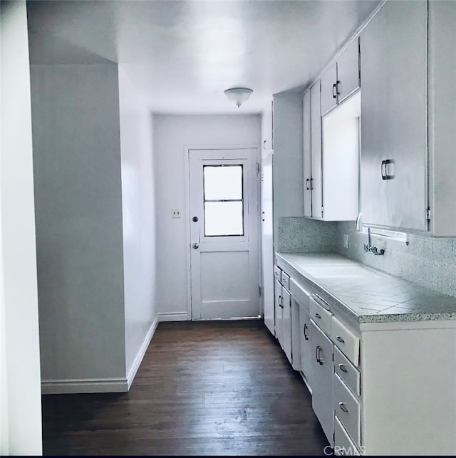 kitchen with backsplash, white cabinetry, dark hardwood / wood-style floors, and sink