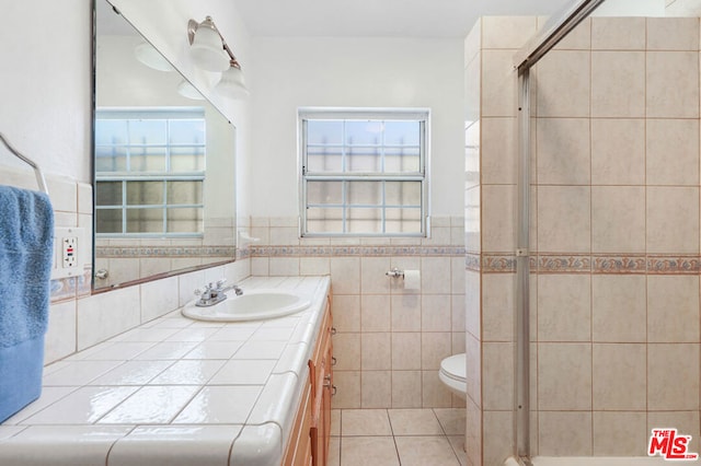 bathroom featuring vanity, toilet, walk in shower, tile walls, and tile patterned flooring