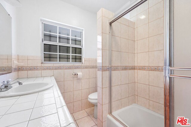 full bathroom with tile patterned flooring, combined bath / shower with glass door, vanity, and toilet