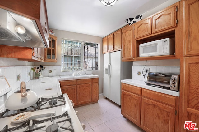 kitchen featuring light tile patterned floors, white appliances, ventilation hood, tile countertops, and decorative backsplash