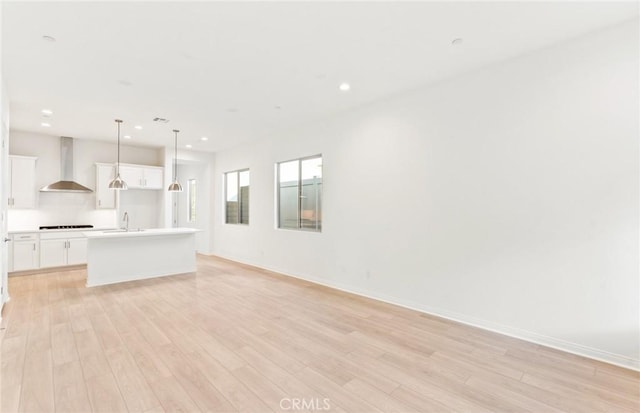 unfurnished living room featuring sink and light hardwood / wood-style floors