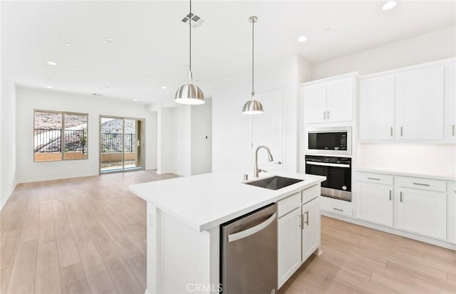 kitchen featuring sink, stainless steel appliances, an island with sink, and white cabinets