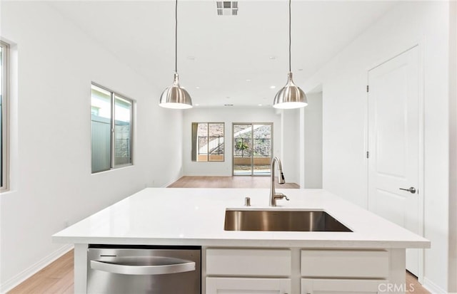 kitchen featuring white cabinetry, sink, stainless steel dishwasher, and a center island with sink