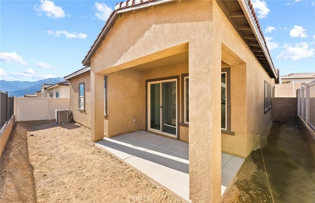 back of property with central AC unit, a patio, and a mountain view