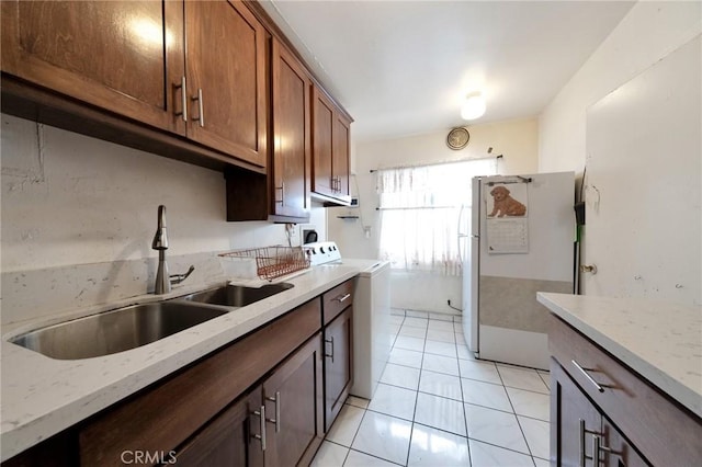 kitchen with light stone counters, sink, white fridge, and light tile patterned floors