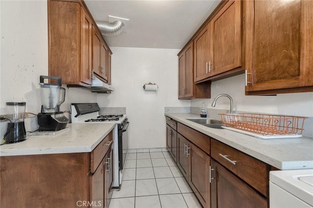 kitchen featuring light stone countertops, range, light tile patterned flooring, and sink