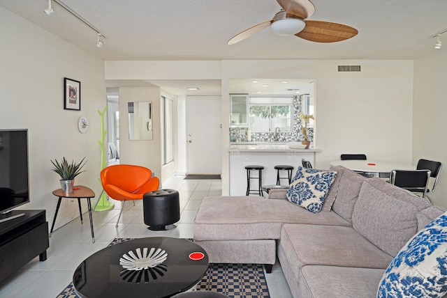 tiled living room featuring ceiling fan, sink, and track lighting