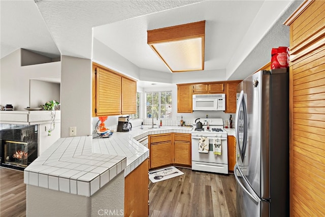 kitchen featuring kitchen peninsula, tile countertops, dark hardwood / wood-style floors, and white appliances