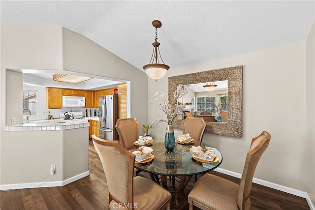 dining area featuring dark hardwood / wood-style floors, sink, and vaulted ceiling