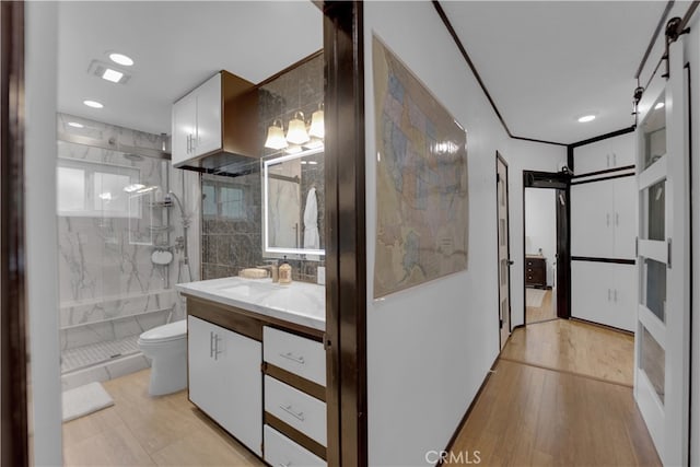 bathroom featuring vanity, toilet, tiled shower, hardwood / wood-style floors, and decorative backsplash