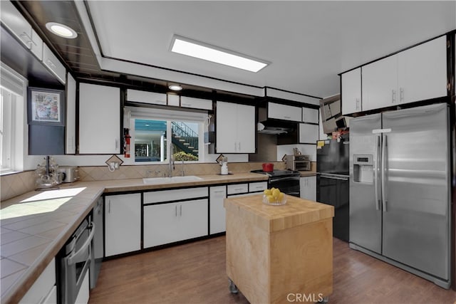 kitchen with a center island, dark wood-type flooring, sink, white cabinetry, and appliances with stainless steel finishes