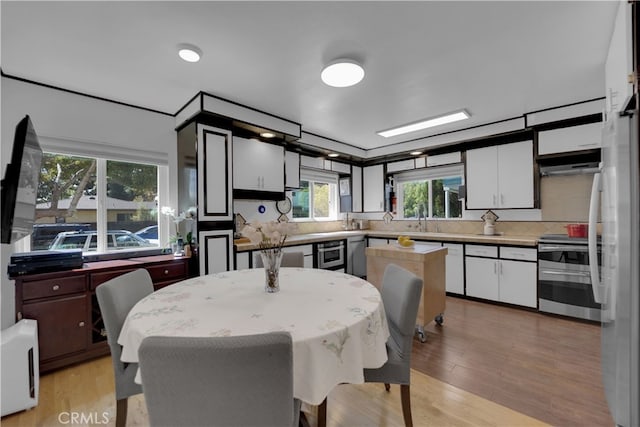 kitchen featuring light wood-type flooring, stainless steel range oven, a kitchen island, and plenty of natural light