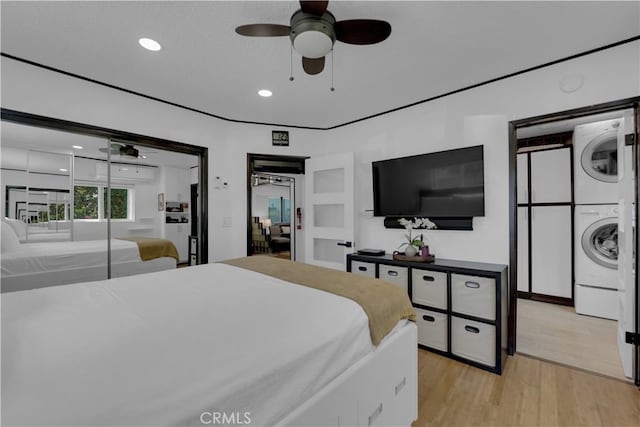 bedroom featuring light hardwood / wood-style floors, ceiling fan, stacked washer / dryer, and a textured ceiling