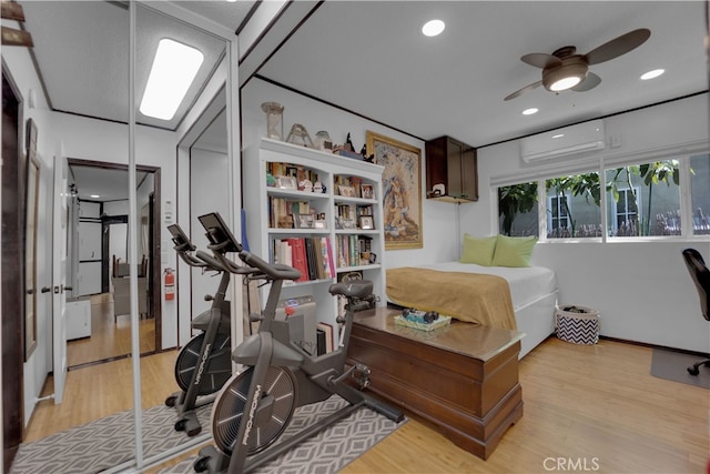 exercise room featuring ceiling fan, light hardwood / wood-style flooring, and a wall mounted air conditioner