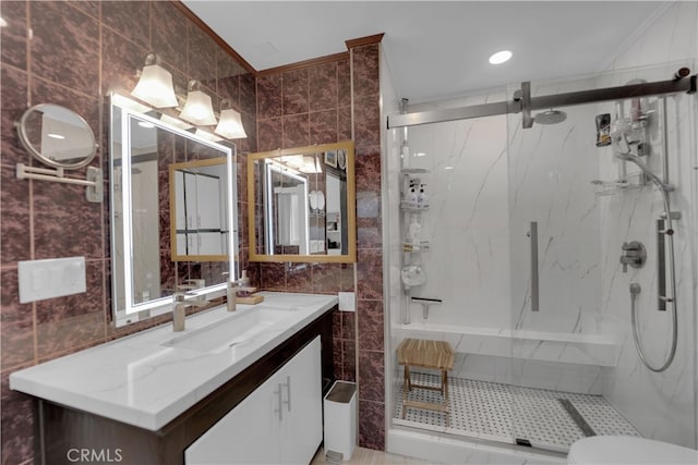 bathroom with tile walls, vanity, toilet, and a shower with door