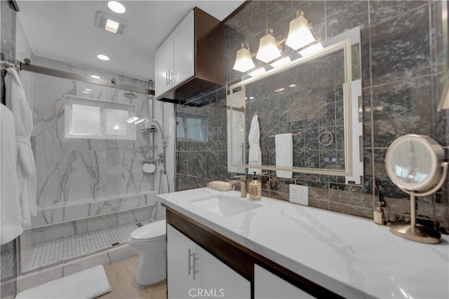 bathroom featuring tile walls, walk in shower, vanity, and toilet