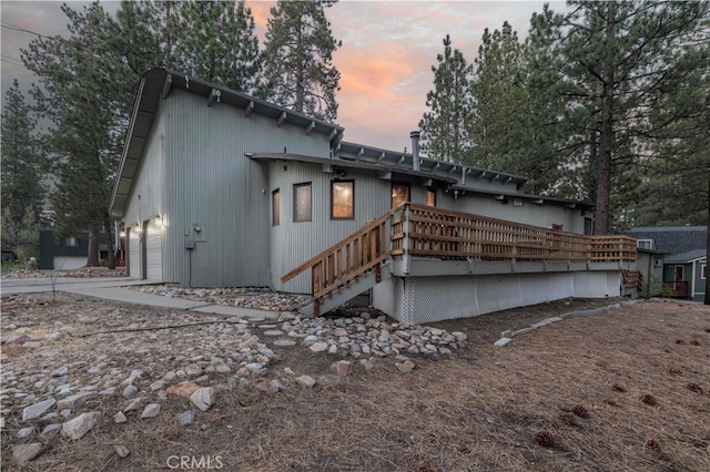 back house at dusk featuring a deck and a garage