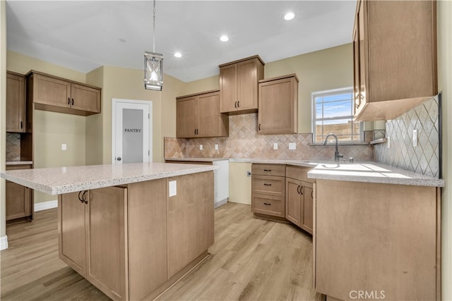 kitchen with light wood-type flooring, a center island, sink, hanging light fixtures, and decorative backsplash